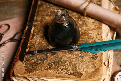 Foto Old book with nib pen, inkwell and scroll on wooden background