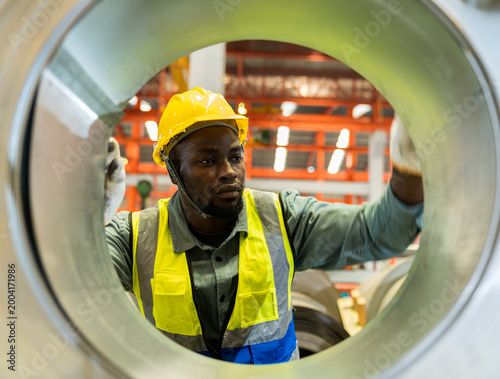 Young man engineer working hard in factory. Metal Sheet industry.
