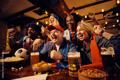 Foto Passionate soccer fans having fun while watching match on TV in pub