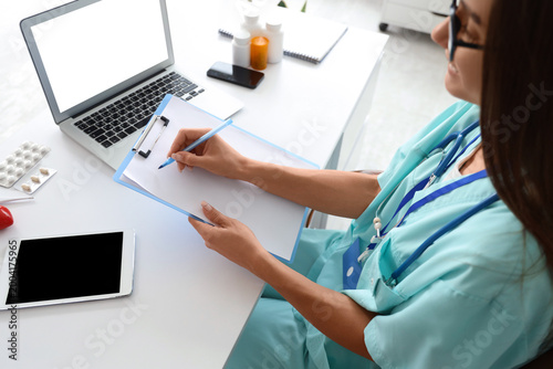 Young female doctor writing...