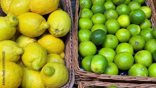 Whole citrus lemons and limes close up, rotate vibrant fruit display at an outdoor market in Singapore, under bright, natural lighting with a handheld camera perspective