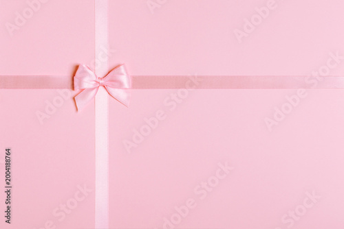 Pink satin ribbon and bow on pink background with copy space