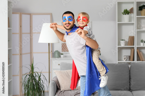 Happy father with his little son dressed as superheroes having fun at home