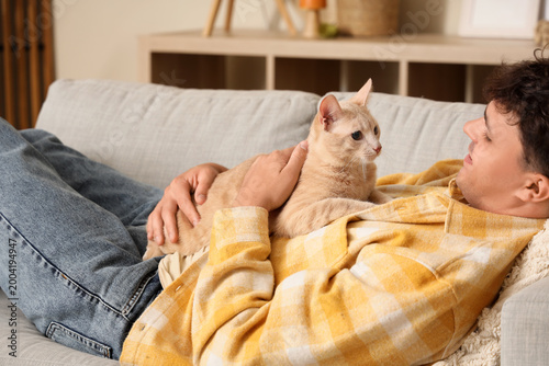 Young man with cute cat lyi...