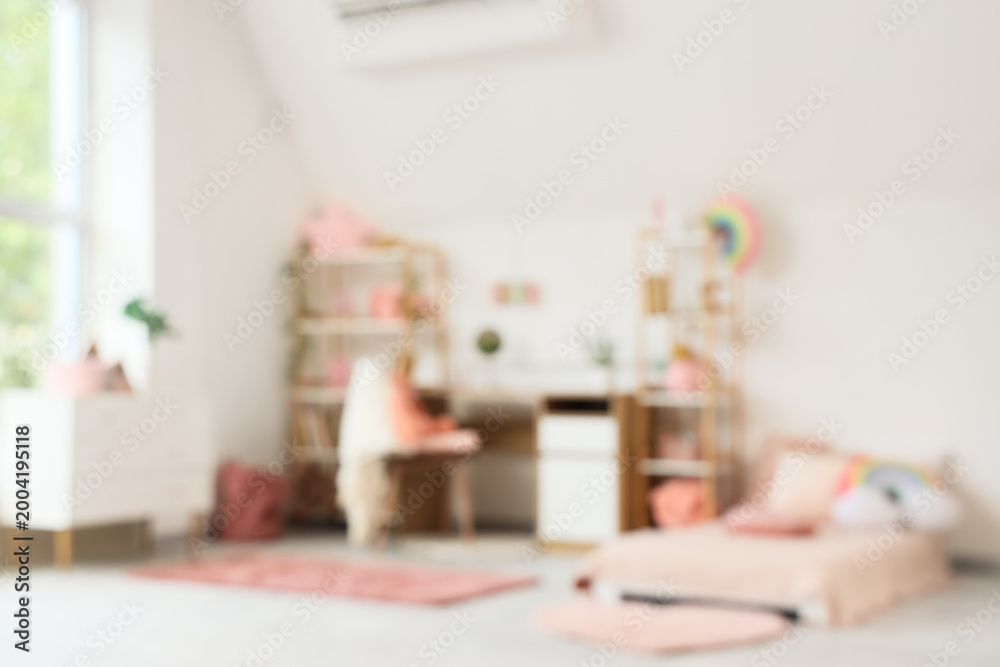 Fototapeta premium Blurred view of children's room with bed, study table and shelf units