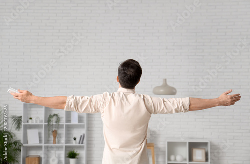 Handsome young man relaxing with operating air conditioner in living room