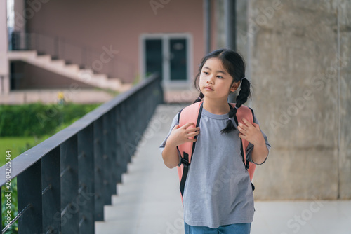 Slika na platnu Thoughtful young girl with backpack walking in modern urban setting, bright day,