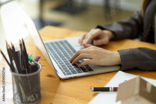 Canvastavla person typing on laptop at wooden desk with stationery and notebook in workspace
