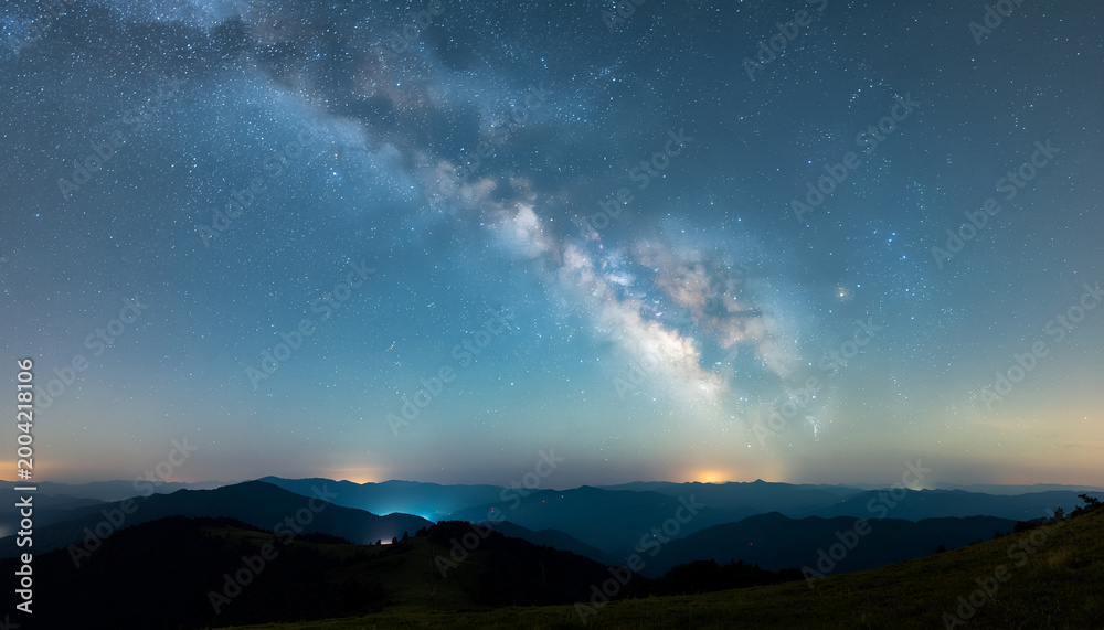 Fototapeta premium Milky Way arcing over tranquil mountain ridge at night.
