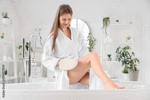 Photos Young woman with glove massaging her leg in bathroom