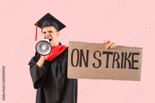 Protesting male graduate shouting into megaphone and holding placard with tex...