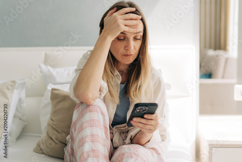 Upset mature woman looking at her mobile phone at a health monitoring application.
