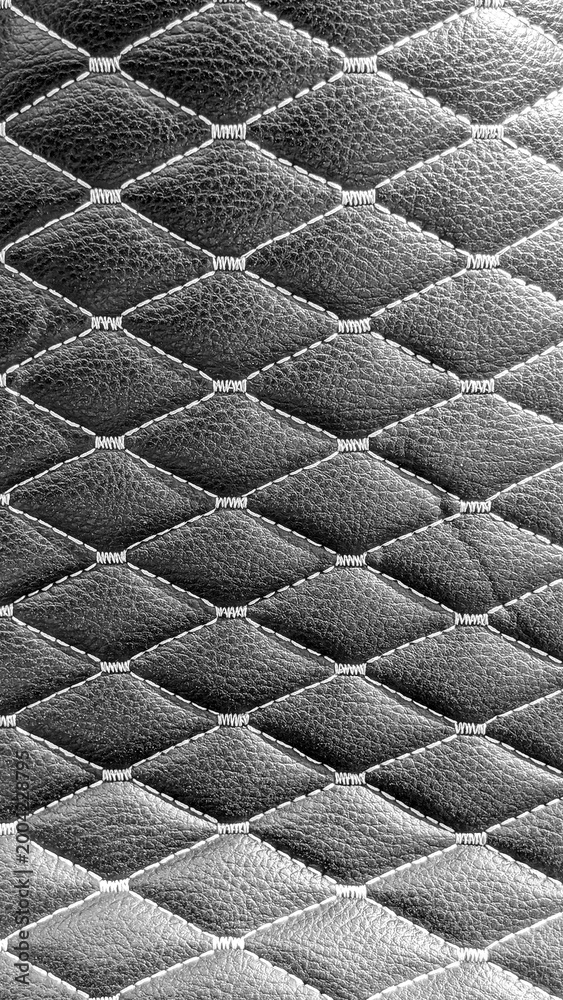 Fototapeta premium Black leather quilted upholstery with white stitching creating a diamond pattern, representing luxury, elegance, comfort, and high quality craftsmanship in design and fashion texture
