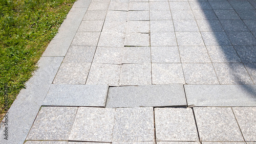 Photos Damaged sidewalk paving causing a trip hazard, uneven gray granite blocks showin