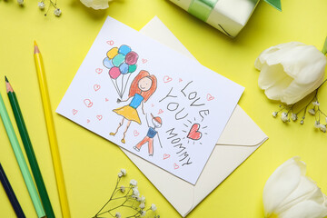 Flowers with kid drawing, pencils and gift box on yellow background. Mother's Day celebration