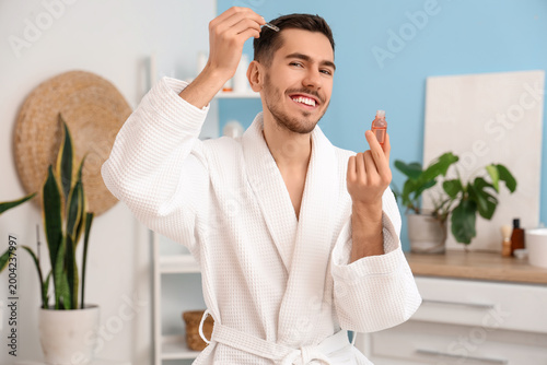 Young man applying serum fo...