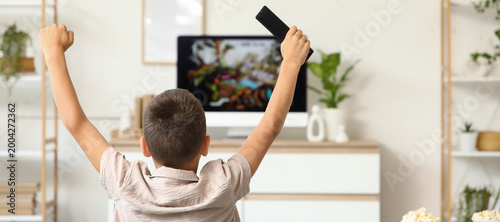 Cute boy with TV remote con...