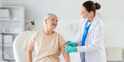 фотографія Senior woman receiving medical patch from doctor after vaccination in clinic