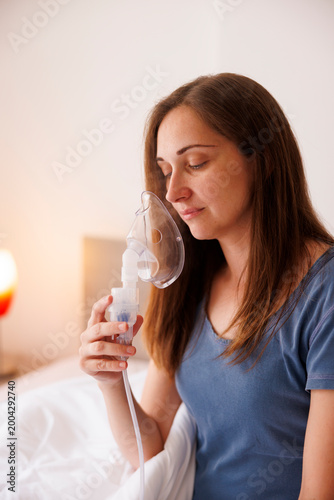 Sick woman taking therapy using inhaler