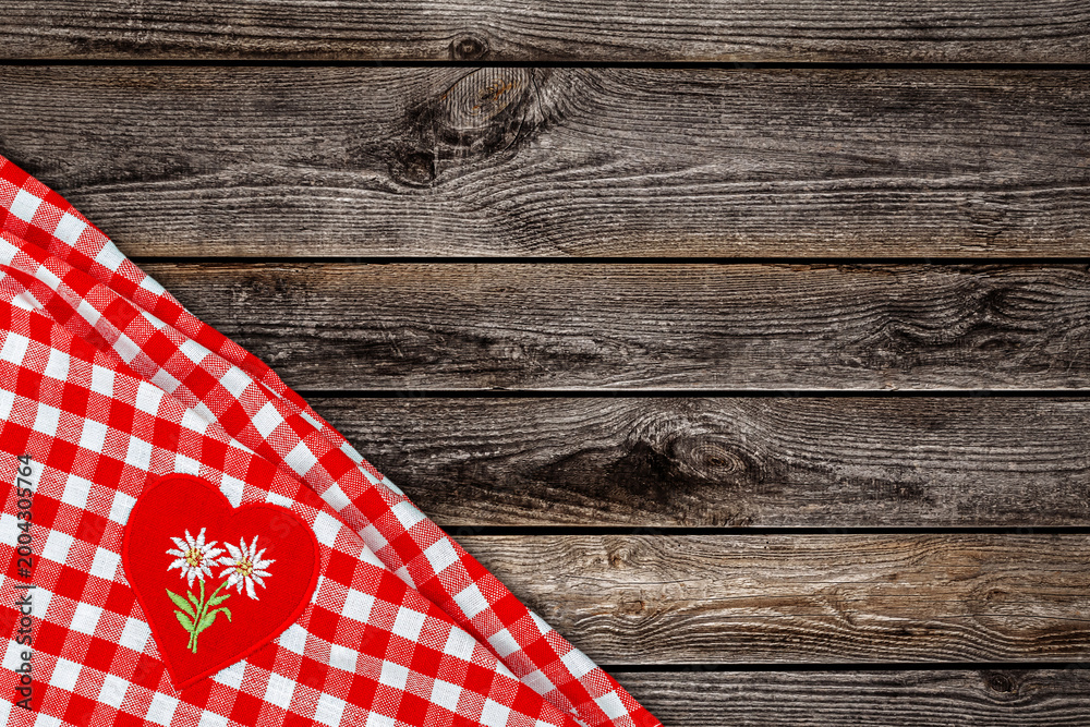 Obraz premium Checkered tablecloth with heart patch placed on rustic wooden table