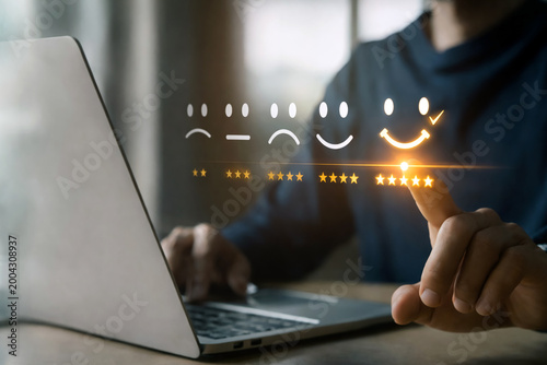Customer feedback interface shows a finger selecting the five star rating icon on a laptop screen representing high satisfaction levels and excellent service quality.