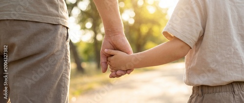 child adult support walking hands family care trust closeup with caregiver and child holding hands on sunlit path suggesting guidance protection connection and safe childhood journey