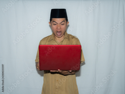 Fotografie A male Indonesian civil servant (PNS) wears a traditional hat and a beige shirt
