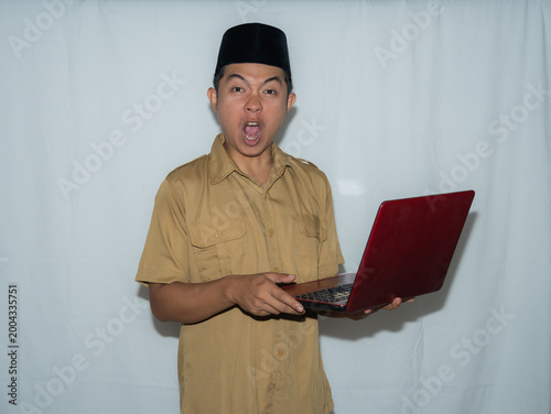 Принти на полотні A male Indonesian civil servant (PNS) wears a traditional hat and a beige shirt