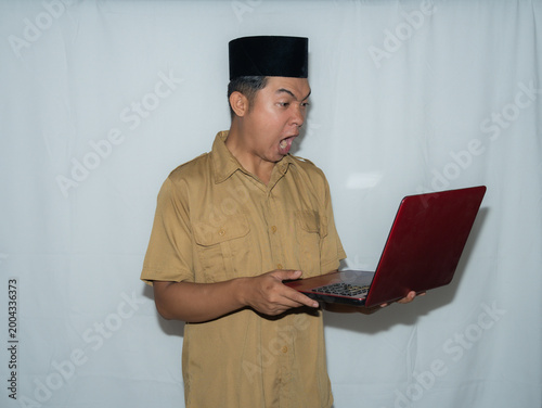 фотографія A male Indonesian civil servant (PNS) wears a traditional hat and a beige shirt