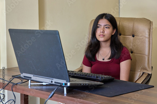 Professional female at workspace with laptop neutral expression focused on task
