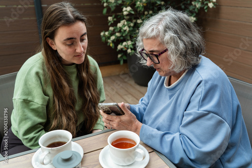 Bild auf Leinwand Senior woman learning smartphone technology from young adult