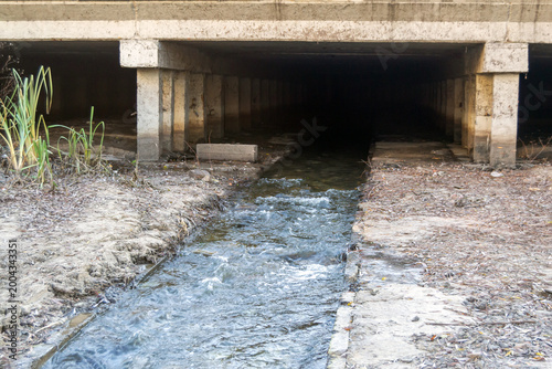 Stream Flowing Through Concrete Culvert Under Bridge