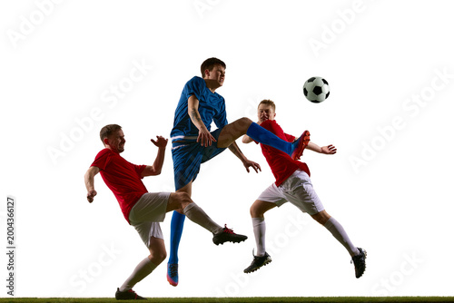 Fotografija Soccer player in blue kicking ball between two red defenders in studio action