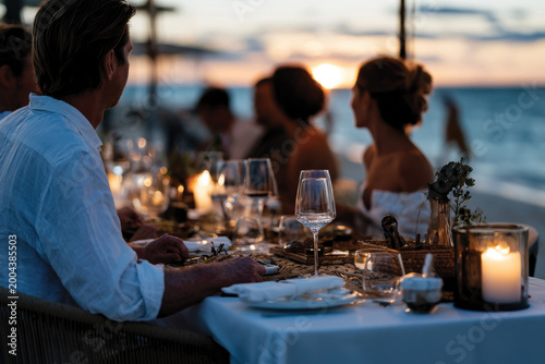 An elegant beach dinner setting showcasing a table adorned with fine dishes and decorative elements, offering guests a tasteful dining experience by the ocean at sunset.