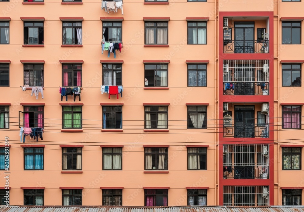 Fototapeta premium Exterior view of a residential building facade showing many windows with hanging laundry.