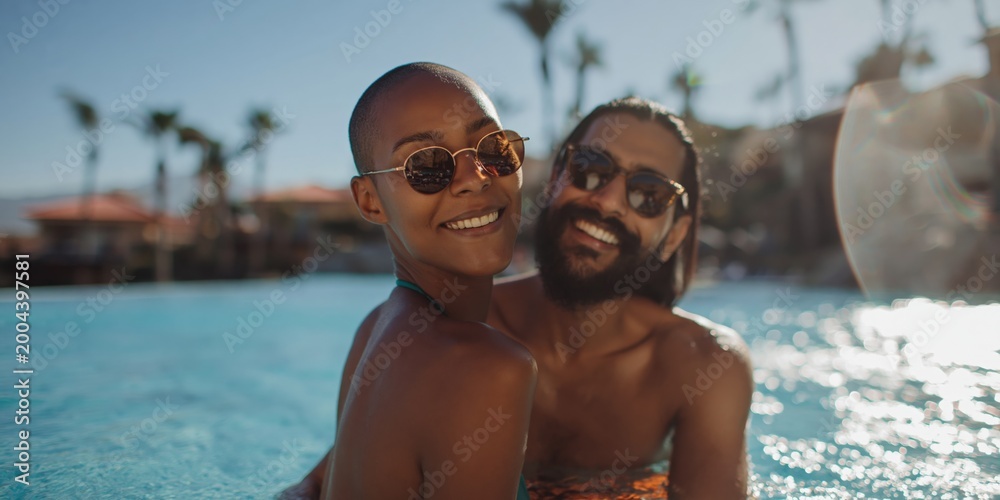 Fototapeta premium Couple smiling and embracing in resort swimming pool