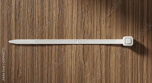 White zip tie on a wooden surface, close-up view, useful for organization and fastening