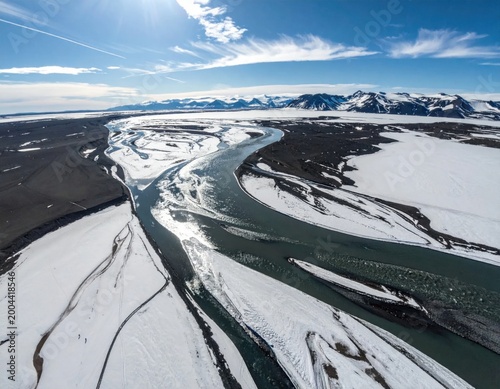 Aerial view of glacial river flowing through arctic landscape with snow covered mountains, climate change, melting ice, wilderness, nature photography