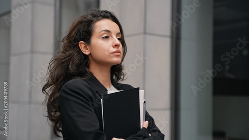 Calm businesswoman walking along the street in the city. Woman holding documents and digital gadget in hands. Lifestyle concept. Real time