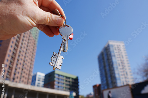 Hand holding keys with crane and new building real estate concept