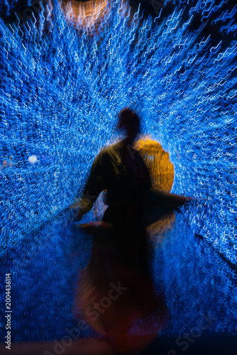 Abstract motion blur of woman silhouette  in glowing blue light tunnel with golden energy core