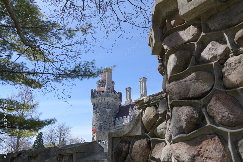 Obraz premium distant view of East Tower at Casa Loma with detail of stone fence, spring morning, Toronto