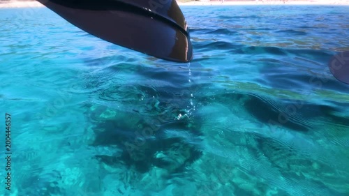Slow motion view of kayak paddle entering crystal clear turquoise water creating gentle splash and ripples in a tropical style seascape