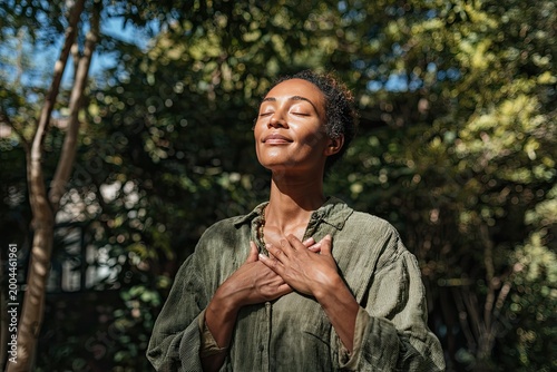 Woman with closed eyes, hands on chest, basking in sunlight