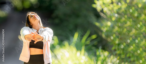 Woman stretching outdoors enjoying morning sun on face