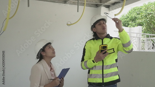 Electrician installing electrical wiring in building construction site with safety equipment