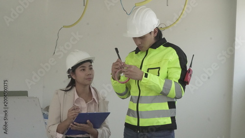 Electrician installing electrical wiring in building construction site with safety equipment