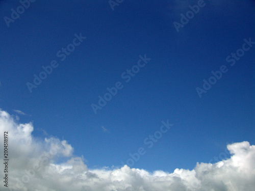 Fotografia Clear blue sky with soft white clouds gathering along the lower edge, creating a calm, minimalist natural background with ample copy space and a sense of openness