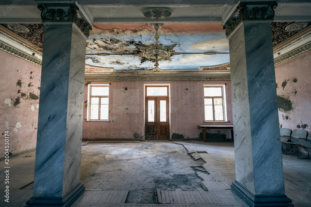 Fototapeta premium Abandoned palace hall with marble columns, damaged ceiling, peeling walls, neoclassical interior, heritage preservation, renovation project.