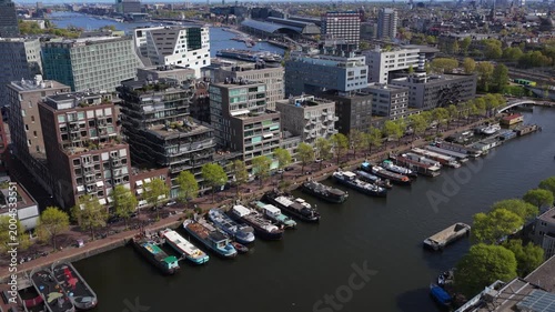 Westerdok Amsterdam skyline showing modern architecture, houseboats on canals, Centraal Station, revealing city's unique urban landscape from above during springtime